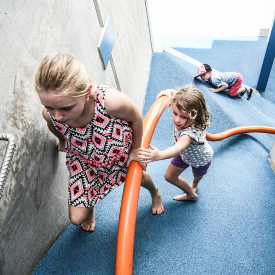 Two children holding a pole to climb a hill